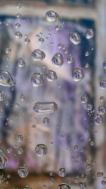 image of water droplets on glass in front of a hokie stone wall